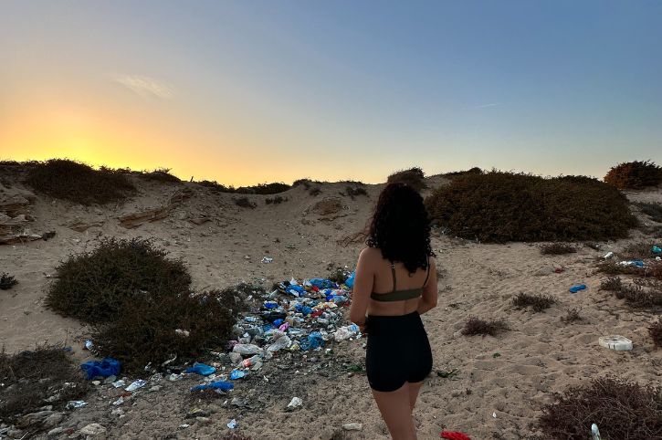 Femme regardant des déchets jetés sur le sable et meditant sur le concept zéro déchet